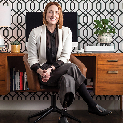 Nadine sits cross legged at her desk, her prosthetic leg in view. 