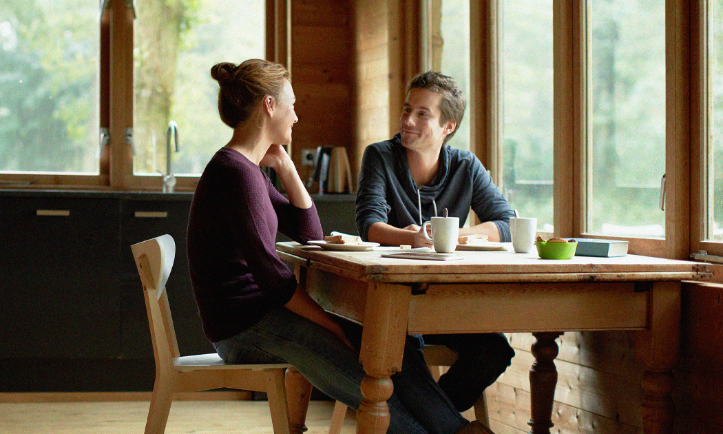 younger couple talking at a kitchen table