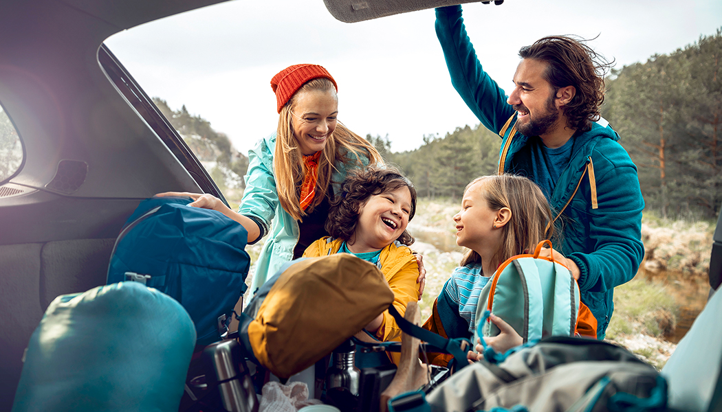 candid shot of a family laughing in front of a car